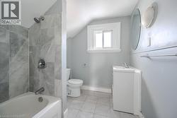 Full bathroom with tile patterned floors, toilet, vaulted ceiling, tiled shower / bath, and vanity - 