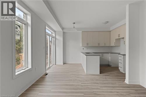 Kitchen featuring a peninsula, dark countertops, light wood finished floors, cream cabinetry, and hanging light fixtures - 13 Davinci Boulevard, Hamilton, ON - Indoor Photo Showing Kitchen