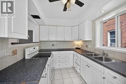 Kitchen featuring white range with electric cooktop, light tile patterned floors, dark countertops, and white cabinets - 