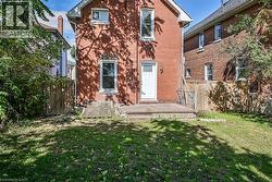 Rear view of house featuring a fenced backyard, brick siding, and a wooden deck - 