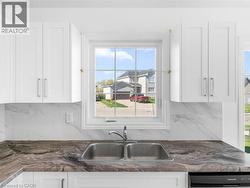 Kitchen featuring backsplash, white cabinetry, dark stone countertops, and healthy amount of natural light - 
