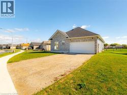 View of front facade with a front lawn, dirt driveway, brick siding, a garage, and roof with shingles - 