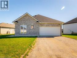 View of front facade featuring dirt driveway, a front lawn, brick siding, and an attached garage - 