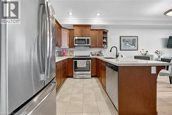 Kitchen with stainless steel appliances, a peninsula, tasteful backsplash, light stone counters, and ornamental molding - 