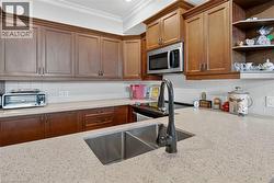 Kitchen with backsplash, open shelves, stainless steel microwave, ornamental molding, and light stone counters - 