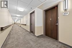 Hallway with light carpet and a drop ceiling - 