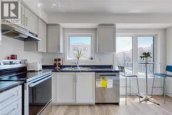 Kitchen with appliances with stainless steel finishes, dark countertops, under cabinet range hood, and light wood finished floors - 