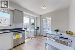 Kitchen with stainless steel dishwasher, dark countertops, light wood-type flooring, and plenty of natural light - 
