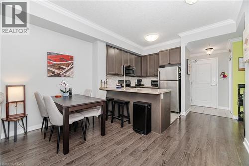 Kitchen with a peninsula, dark brown cabinetry, stainless steel appliances, crown molding, and dark wood-style flooring - 5317 Upper Middle Road Unit# 112, Burlington, ON - Indoor