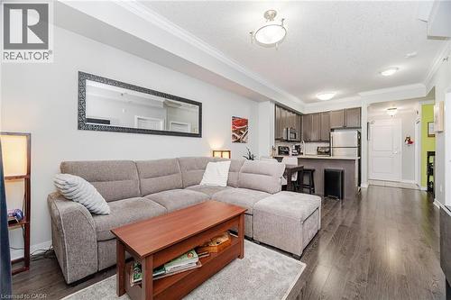Living area with dark wood finished floors, ornamental molding, and a textured ceiling - 5317 Upper Middle Road Unit# 112, Burlington, ON - Indoor Photo Showing Living Room