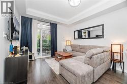 Living area with a tray ceiling, crown molding, and dark wood-type flooring - 