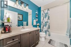 Bathroom featuring shower / tub combo with curtain, light tile patterned floors, and vanity - 