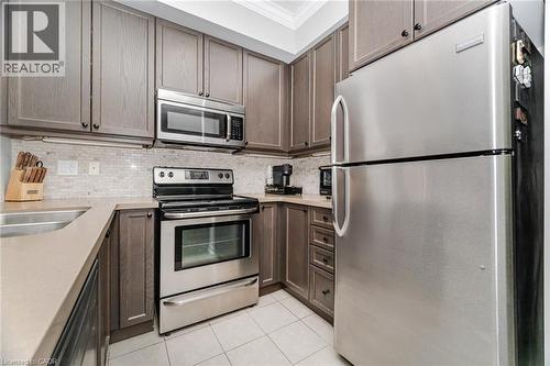 Kitchen featuring appliances with stainless steel finishes, crown molding, backsplash, light tile patterned flooring, and dark brown cabinets - 5317 Upper Middle Road Unit# 112, Burlington, ON - Indoor Photo Showing Kitchen With Double Sink With Upgraded Kitchen