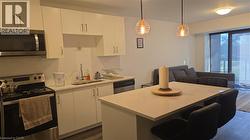Kitchen featuring appliances with stainless steel finishes, light countertops, white cabinetry, a breakfast bar, and dark wood-type flooring - 