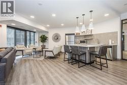 Kitchen featuring open floor plan, hanging light fixtures, a breakfast bar area, backsplash, and freestanding refrigerator - 