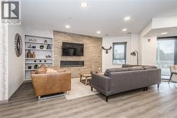 Living room featuring light wood finished floors, recessed lighting, a tiled fireplace, and built in shelves - 