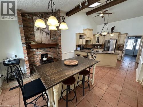 Dining space featuring a chandelier, a textured ceiling, a ceiling fan, light tile patterned floors, and high vaulted ceiling - 5590 Blind Line, Burlington, ON - Indoor Photo Showing Dining Room With Fireplace