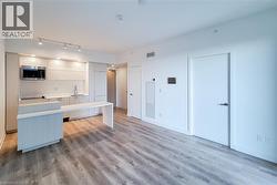 Kitchen with modern cabinets, light wood-style floors, stainless steel microwave, rail lighting, and white cabinetry - 