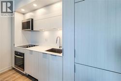 Kitchen with modern cabinets, stainless steel appliances, light wood finished floors, recessed lighting, and white cabinetry - 