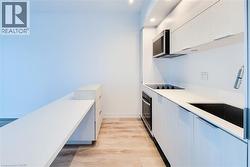 Kitchen featuring modern cabinets, light wood-style floors, white cabinetry, and recessed lighting - 