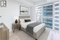 Bedroom with light wood-style floors and floor to ceiling windows - 