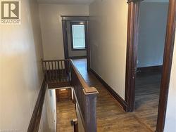 Hall featuring an upstairs landing and dark wood-style flooring - 