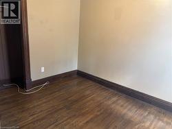 Spare room featuring dark wood-style flooring and baseboards - 