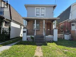 View of front of property featuring brick siding, covered porch, a front yard, and stucco siding - 