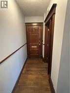 Hallway with dark wood-style flooring and a textured ceiling - 