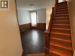 Staircase with a textured ceiling, wood-type flooring, wainscoting, and wood walls - 