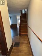 Hallway with dark wood finished floors, a textured ceiling, stairs, and wainscoting - 