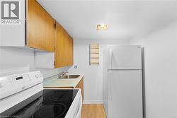 Kitchen featuring white appliances, light countertops, brown cabinetry, and light wood-type flooring - 