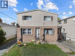 View of front facade with brick siding, a front lawn, and stucco siding - 