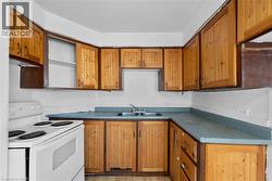 Kitchen featuring white electric range oven, brown cabinets, light wood-style flooring, and dark countertops - 