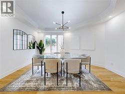 Dining room with a raised ceiling, light wood-style flooring, recessed lighting, a chandelier, and crown molding - 
