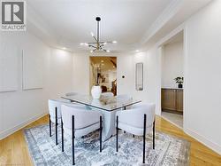 Dining room with a tray ceiling, light wood-style floors, crown molding, a chandelier, and recessed lighting - 