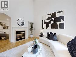 Living room featuring wood finished floors, a fireplace, arched walkways, a high ceiling, and recessed lighting - 