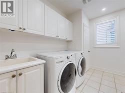 Laundry room with light tile patterned floors, washer and clothes dryer, recessed lighting, and cabinet space - 