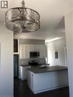 Kitchen with dark countertops, range, fridge, white cabinets, and electric panel - 