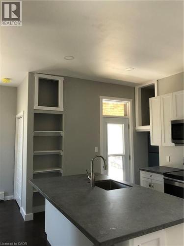 Kitchen with dark countertops, white cabinetry, an island with sink, dark wood-style floors, and stove - 552 7Th Avenue, Hanover, ON - Indoor Photo Showing Kitchen