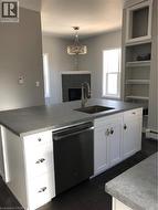 Kitchen with dishwashing machine, a tile fireplace, white cabinetry, and dark wood-type flooring - 
