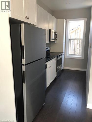 Kitchen featuring freestanding refrigerator, range, dark countertops, dark wood-style flooring, and white cabinetry - 552 7Th Avenue, Hanover, ON - Indoor Photo Showing Kitchen