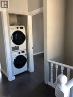 Laundry area featuring stacked washer and clothes dryer and wood finished floors - 
