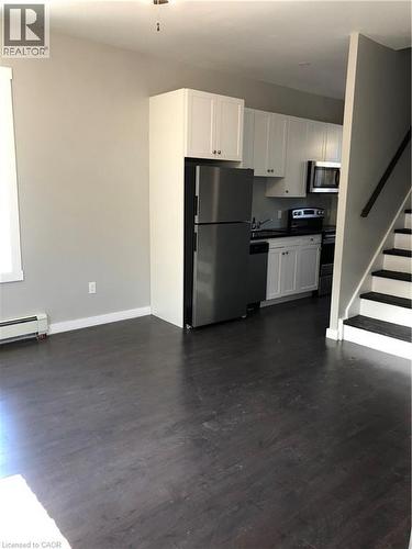 Kitchen with fridge, dark wood-style floors, stove, a baseboard radiator, and white cabinetry - 552 7Th Avenue, Hanover, ON - Indoor Photo Showing Kitchen