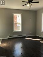 Spare room with dark wood-type flooring, baseboard heating, and ceiling fan - 