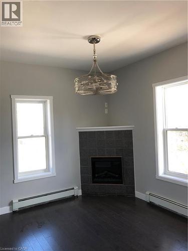 Unfurnished living room with a baseboard radiator, dark wood-type flooring, and plenty of natural light - 552 7Th Avenue, Hanover, ON - Indoor Photo Showing Living Room With Fireplace