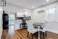 Dining room featuring wood finished floors, plenty of natural light, a wall unit AC, and recessed lighting - 