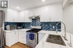 Kitchen with white cabinetry, electric range, tasteful backsplash, and recessed lighting - 