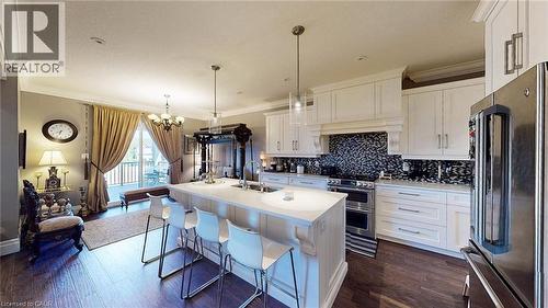 Kitchen with high quality fridge, white cabinetry, backsplash, a chandelier, and crown molding - 537 Millstream Drive, Waterloo, ON - Indoor Photo Showing Kitchen With Double Sink With Upgraded Kitchen