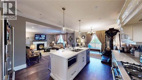 Kitchen with open floor plan, decorative light fixtures, white cabinets, stainless steel appliances, and crown molding - 537 Millstream Drive, Waterloo, ON - Indoor Photo Showing Kitchen With Double Sink With Upgraded Kitchen